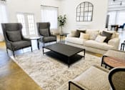 Thumbnail 4 of 8 - A living room with a grey sofa, two grey armchairs, a black coffee table, and a rug.