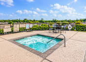 Thumbnail 2 of 8 - A hot tub sits in the middle of a patio surrounded by a fence.