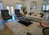 Thumbnail 6 of 15 - A living room with a grey couch, a black coffee table, and a fireplace.