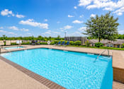Thumbnail 3 of 8 - A large blue swimming pool surrounded by a fence and trees.