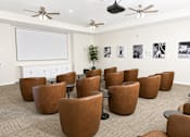 Thumbnail 5 of 8 - A room with brown chairs and a white screen on the wall.
