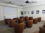 Thumbnail 4 of 15 - A room with brown chairs and a white screen on the wall.
