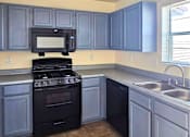 Thumbnail 3 of 7 - A kitchen with a black stove and cabinets.