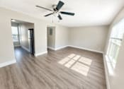 Thumbnail 2 of 5 - A spacious room with a ceiling fan and a refrigerator.