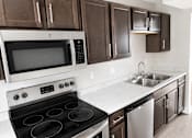 Thumbnail 3 of 5 - A modern kitchen with dark brown cabinets and stainless steel appliances.