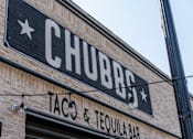 Thumbnail 16 of 25 - A brick building with a sign that says Chubbs Taco & Tequila Bar.