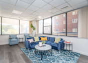 Thumbnail 6 of 23 - a living room with blue couches and a coffee table in front of large windows