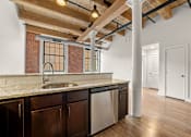 Thumbnail 16 of 18 - A kitchen with a brick wall and wooden beams.