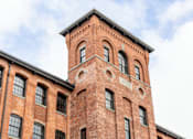 Thumbnail 17 of 18 - A red brick building with a tower and windows.