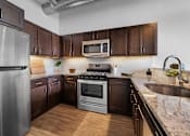 Thumbnail 15 of 18 - A kitchen with dark wood cabinets and stainless steel appliances.