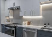 Thumbnail 22 of 25 - a kitchen with white cabinets and gray countertops