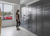 Thumbnail 18 of 25 - a woman in a black shirt and black leggings opens a drawer in a gray locker