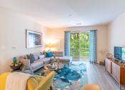 Thumbnail 6 of 28 - a living room with a couch and a tv and a sliding glass door