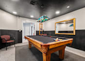 Thumbnail 25 of 39 - A pool table with a red chair and a mirror in a room.