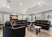 Thumbnail 20 of 39 - A black leather couch in a room with wooden floors and white walls.