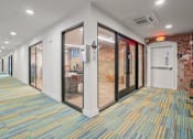 Thumbnail 21 of 29 - A hallway with a carpeted floor and glass doors.
