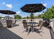 Thumbnail 29 of 39 - A wooden deck with a table and chairs under umbrellas.