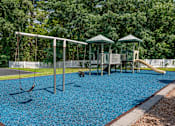 Thumbnail 32 of 39 - A playground with a blue rubberized surface and a swing set.