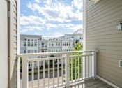 Thumbnail 17 of 35 - A balcony with a white railing overlooks a street with buildings in the background.