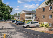 Thumbnail 38 of 39 - A parking lot with cars and a building in the background.