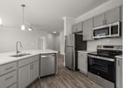 Thumbnail 4 of 35 - A modern kitchen with stainless steel appliances and wooden floors.