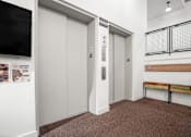 Thumbnail 22 of 29 - A hallway with two elevators and a bench.