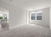 Thumbnail 7 of 35 - A spacious, empty room with a carpeted floor and two windows.