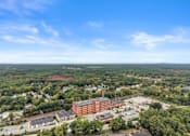 Thumbnail 29 of 29 - A large red brick building sits in the middle of a green landscape.