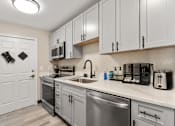 Thumbnail 22 of 39 - A kitchen with a white door and a stainless steel dishwasher.