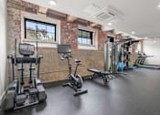 Thumbnail 18 of 29 - A gym with a brick wall and various exercise equipment.