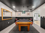 Thumbnail 21 of 39 - A pool table in a room with a mirror on the wall.