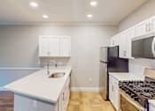 Thumbnail 15 of 26 - A kitchen with white cabinets and a black refrigerator.