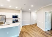 Thumbnail 14 of 26 - A kitchen with a white counter top and wooden floors.