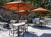 Thumbnail 5 of 21 - A patio with a table and chairs under umbrellas.