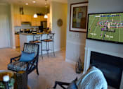Thumbnail 15 of 21 - A living room with a fireplace and a television showing a football game.