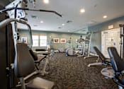 Thumbnail 11 of 21 - A gym with a variety of equipment including treadmills, weights, and exercise machines.