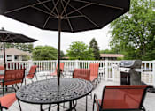 Thumbnail 18 of 23 - A patio with a table and chairs under an umbrella.