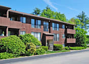 Thumbnail 22 of 23 - A brown building with green bushes in front.
