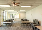 Thumbnail 8 of 12 - A room with tables and chairs and a ceiling fan.