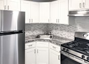 Thumbnail 1 of 5 - A kitchen with white cabinets and a stainless steel refrigerator.