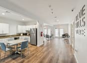Thumbnail 10 of 16 - a dining room with a table and chairs and a kitchen with a stainless steel refrigerator at Blue Hills Village, Massachusetts, 02021
