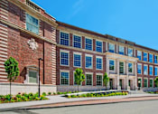 Thumbnail 1 of 16 - a large brick building with many windows and a street in front at Beverly Village for Living & the Arts Apartments, Beverly, 01915