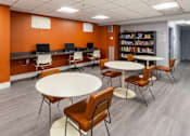 Thumbnail 9 of 12 - a common room with tables and chairs and a library at Mill House Apartments, Greenfield, MA 01301