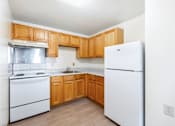 Thumbnail 10 of 12 - Compact kitchen with white appliances and oak cabinets at Blue Ridge Estates Apartments, Richmond, Virginia
