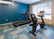 Thumbnail 8 of 12 - A gym with a treadmill and a stationary bike. at 35 Broadway Apartments, Menands, New York