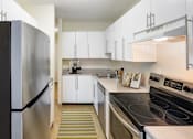 Thumbnail 2 of 16 - a kitchen with white cabinets and stainless steel appliances and a black stove at Blue Hills Village, Canton, 02021
