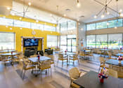 Thumbnail 15 of 15 - Community lounge with dining tables and entertainment area at Baystate Place Apartments, Springfield, MA 1104