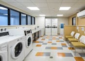 Thumbnail 10 of 15 - Modern laundry facility with washers dryers and seating at Baystate Place Apartments, Springfield, MA 1104