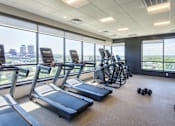 Thumbnail 9 of 15 - Fitness center with cardio equipment and city views at Baystate Place Apartments, Springfield Massachusetts