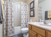 Thumbnail 7 of 14 - A bathroom with a toilet, sink, and shower curtain Fishermans Landing Apartments in Ormond Beach, FL.